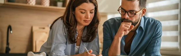 A couple reviewing financing paperwork together at their kitchen counter